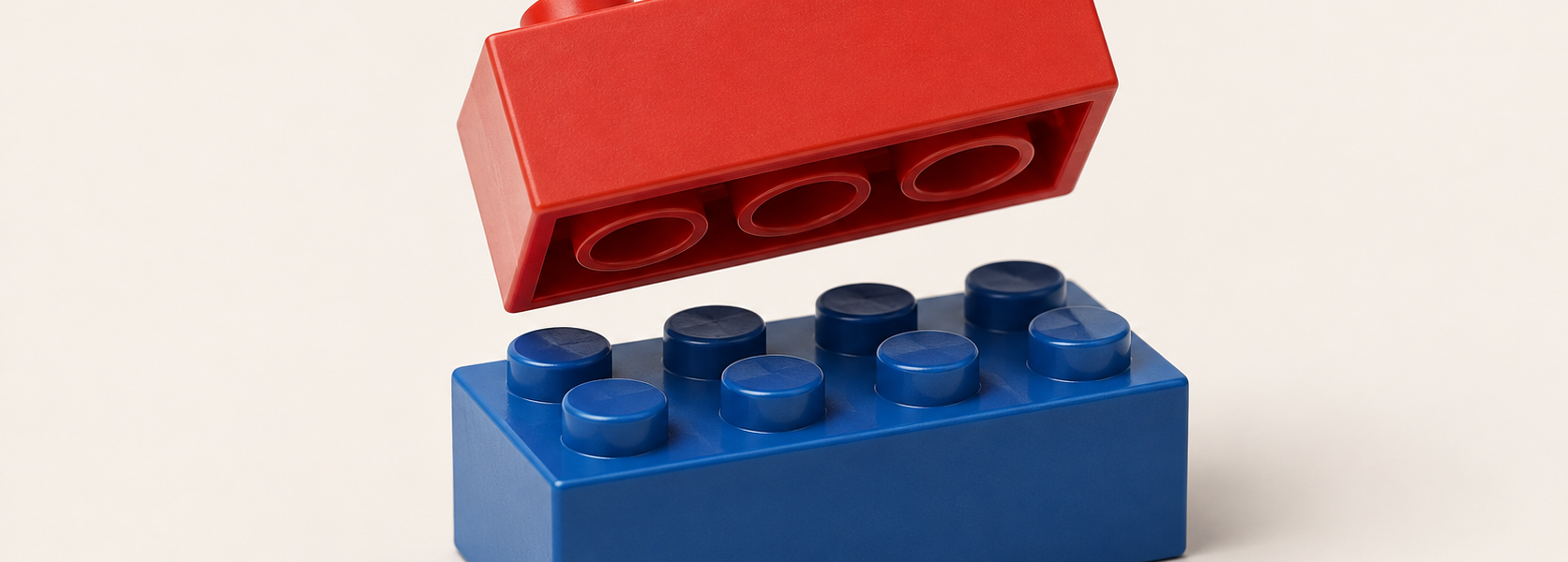 A red construction brick shown from underneath with visible tubes above a blue studded brick, illustrating the stud-and-tube principle.