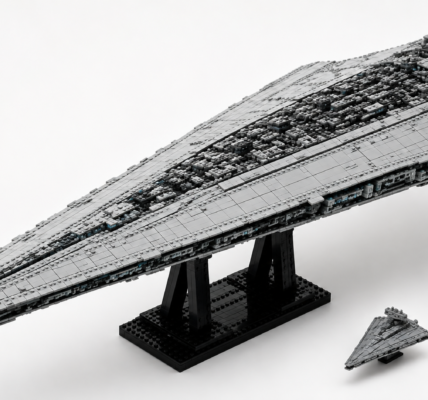 A large gray wedge-shaped brick-built sci-fi starship on a black stand, with a smaller ship beside it to show scale, set against a bright neutral background.