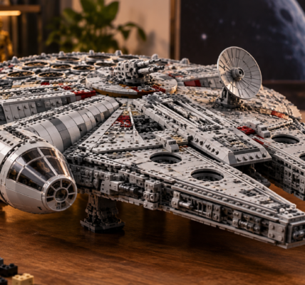 A large gray brick-built spacecraft displayed on a wooden table in a collector-style room.