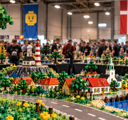 A LEGO fan exhibition hall with a detailed brick-built Danish town, lighthouse, harbor and event attendees in the background.